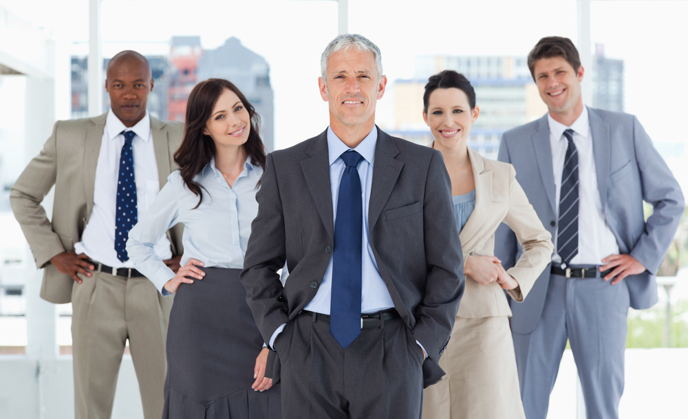 Smiling business team standing upright with their hands on their hips